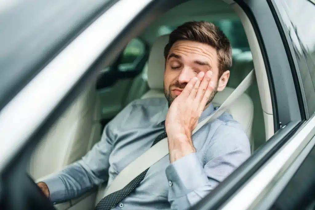 A tired driver rubbing his palm on his face