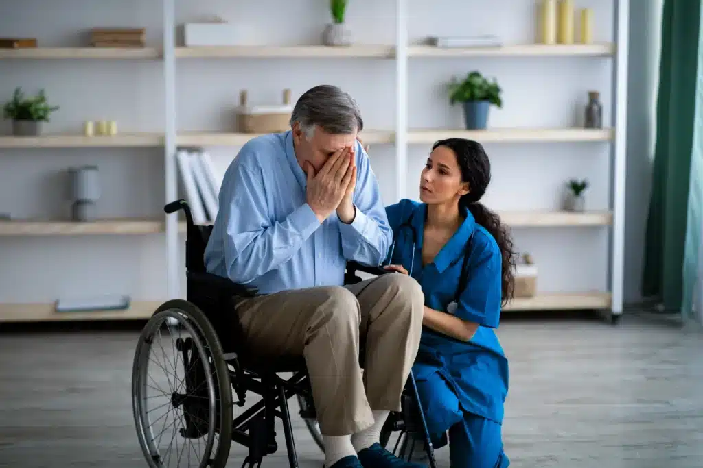 A nurse consoling a crying patient sitting on the wheelchair