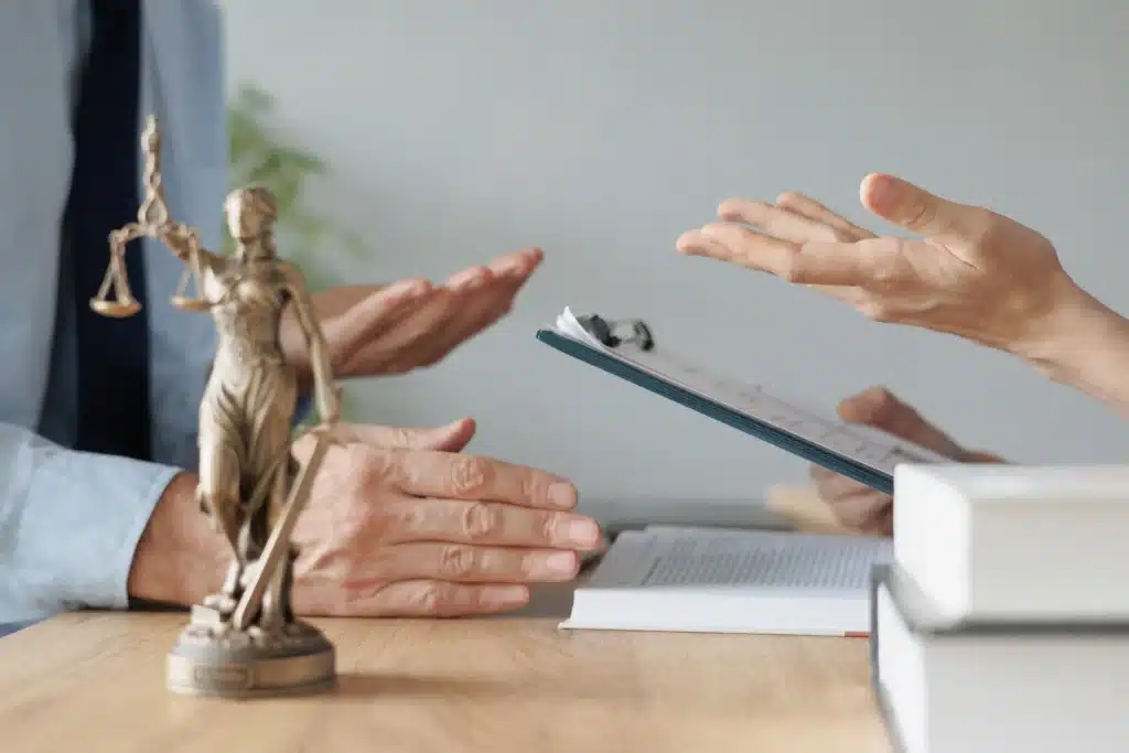 an attorney and a client discussing and a justice symbol on the table