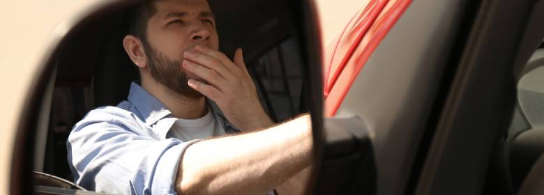 man yawns while driving