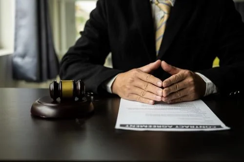 A car accident lawyer sits at his office desk with hands folded.