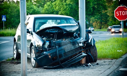 A black car having collided with a post after losing control on the road.