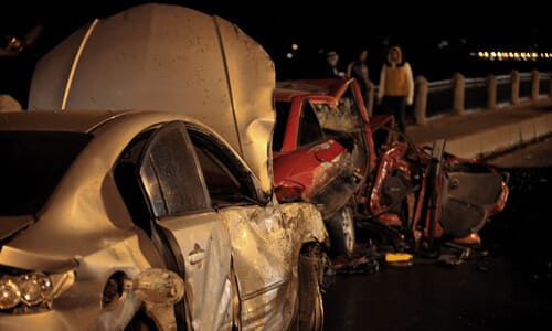 A head on collision between a street racer and another vehicle on a bridge at night.
