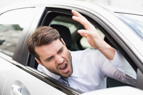 An angry driver yells out of the window of his car.