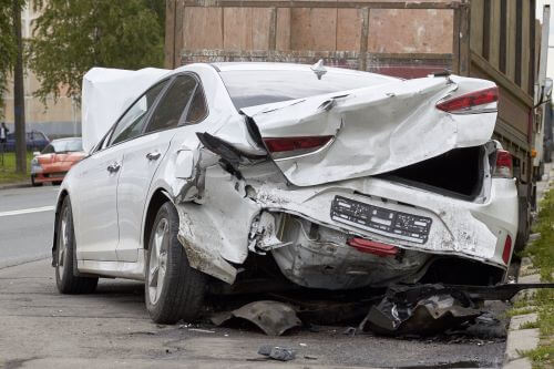 A white car with a damaged back end after a defective car accident.