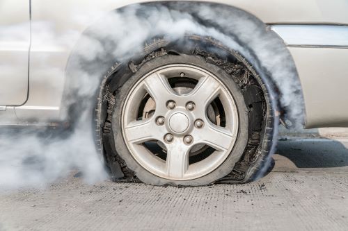 A tire blowout on a grey car.