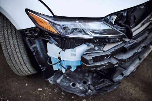 A closeup of a damaged front end of a vehicle after a lane change accident.