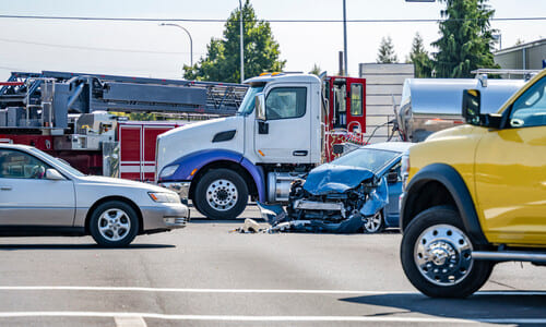 A white fuel truck involved in an accident with a blue family hatchback.