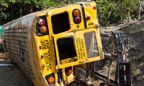 A yellow school bus on its side after tipping over during an accident.