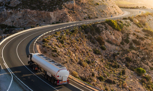 A trucker driving along a winding mountain road in the late afternoon.