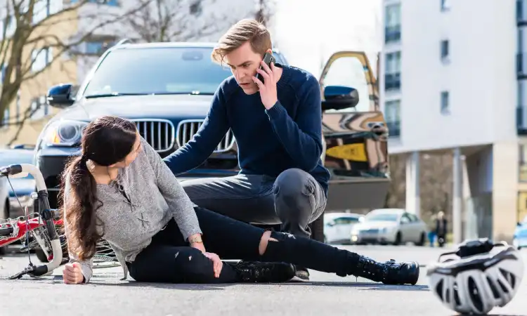 A car driver getting help for a bicyclist after a daytime collision.