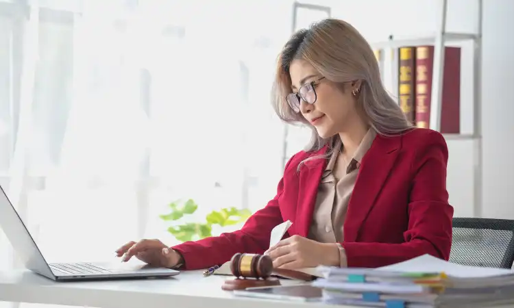 A birth injury lawyer at her desk in a bright office working at a computer.