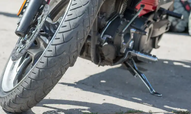 A closeup of a poorly-maintained motorcycle's front wheel.