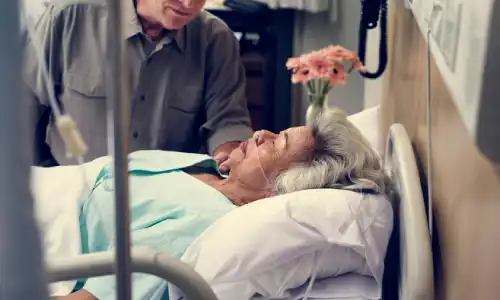 A man visiting his sedated loved one in a nursing home.