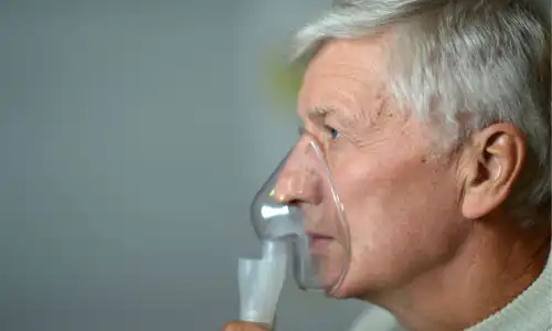 A profile shot of an elderly man with an oxygen mask over his nose and mouth.