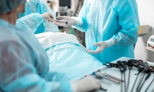 A nurse handing a doctor tools for an ongoing surgery.