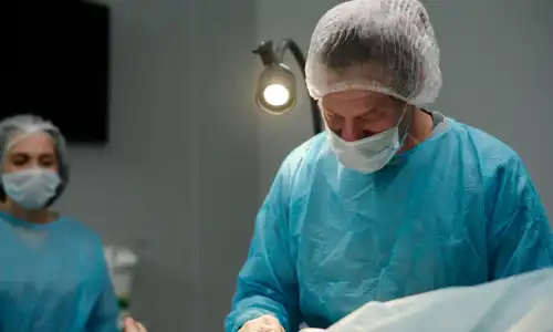 A surgeon performing a procedure with another doctor in the background.