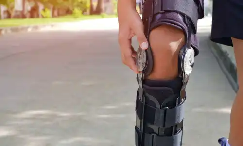 An amputee adjusting his leg while on an afternoon jog.