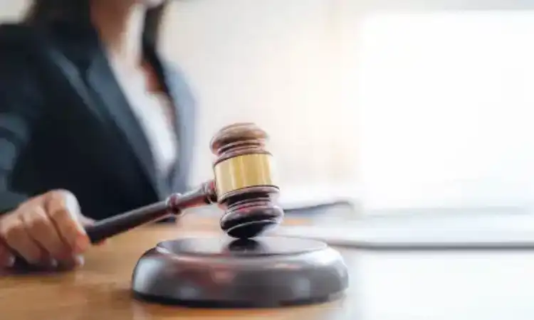 A birth injury lawyer holding a gavel against its soundblock while seated behind her desk.