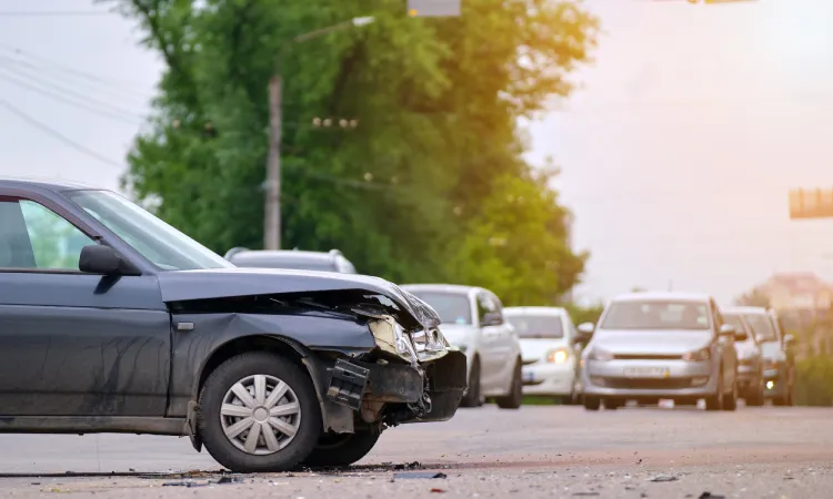 A dark-colored car with a damaged hood causing traffic after an accident with a DUI driver.