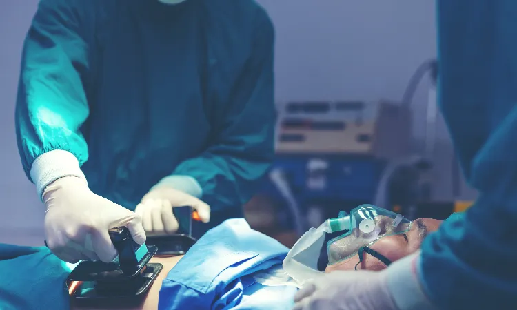 A medical team in an operating theater using a defibrilator to try and revive a patient.