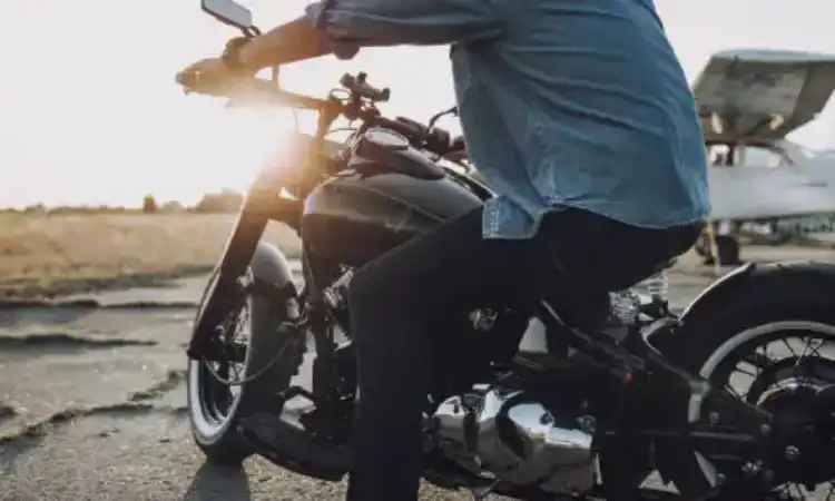 A motorcyclist in the late afternoon driving along a highway.