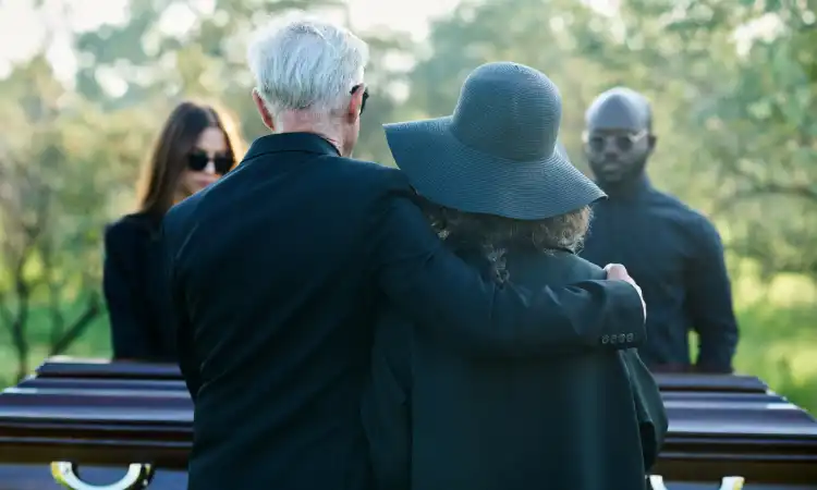 People at a funeral gathered together bidding a deceased loved one a last farewell.