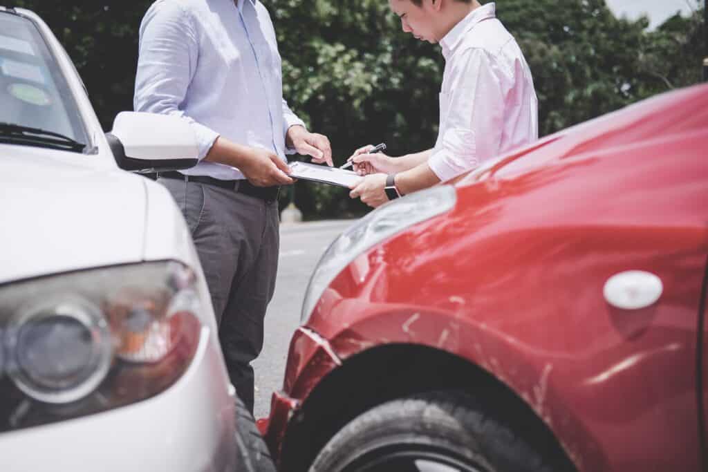 Insurance Agent examine Damaged Car and customer filing signature on Report Claim Form process after accident, Traffic Accident and insurance concept.