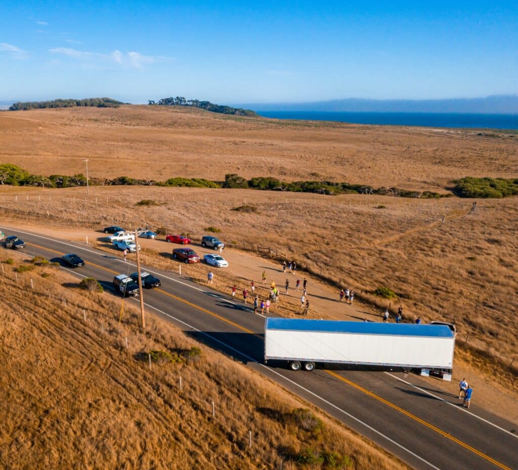An aerial shot of vehicles and people on the highway surrounded by fields