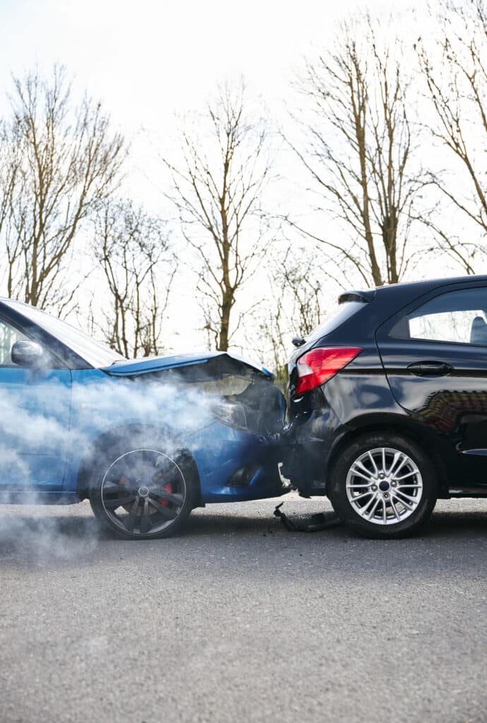 Two cars involved in traffic accident on side of the road with damage to bonnet and fender