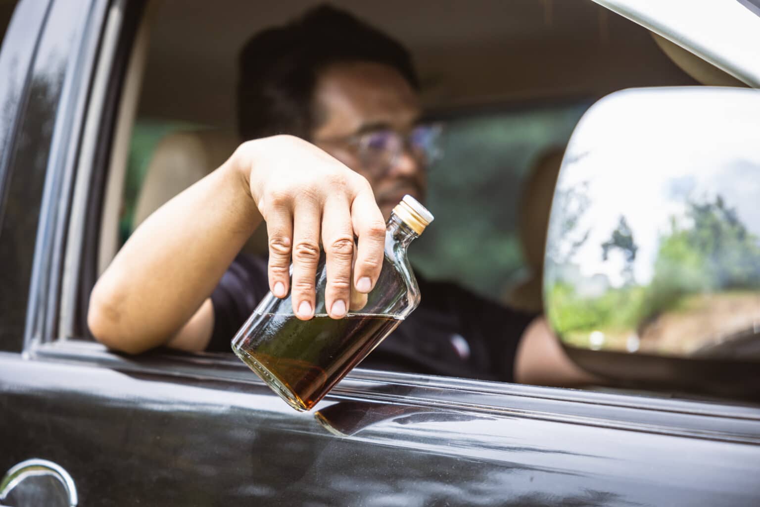 drunk driver holding a bottle of whiskey