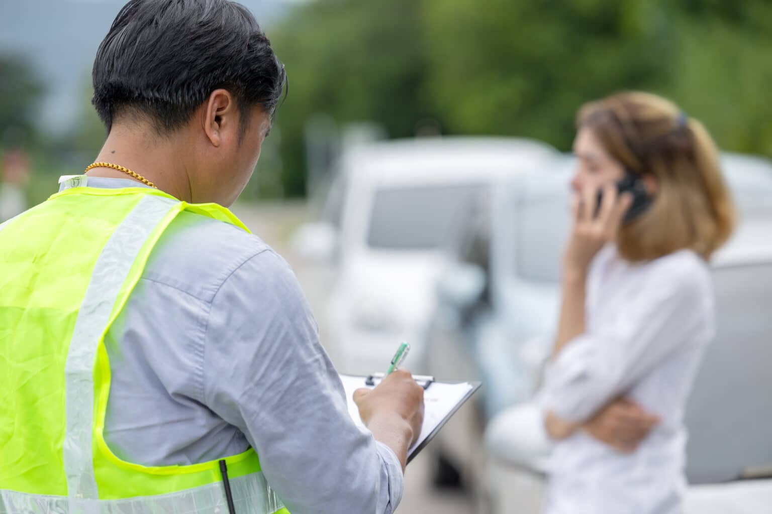 woman on the phone while person files a report for the car accident
