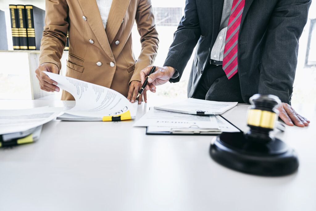 lawyers reviewing and signing legal documents with a gavel on the desk