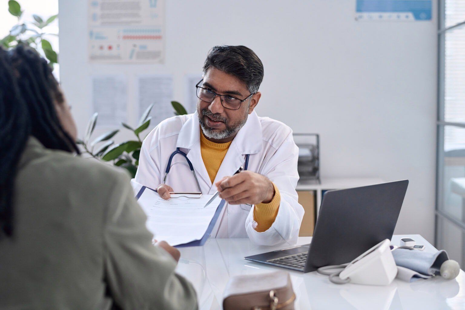 doctor holding clipboard discussing with patient