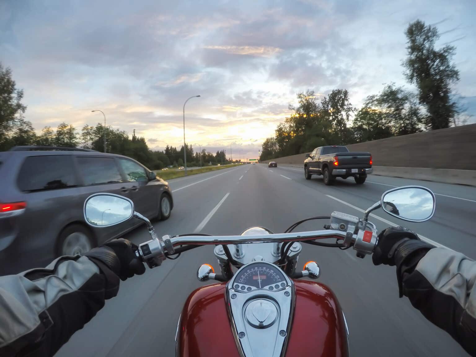 riding motorcycle next to vehicles during sunset