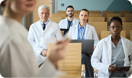 medical professionals attending a lecture in a classroom, listening to a speaker