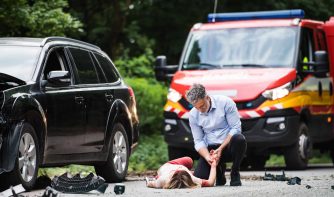 A man helping a young woman lying unconscious after a car accident