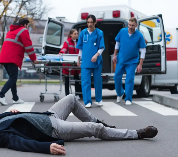 Paramedics walking towards a man lying helplessly on the road