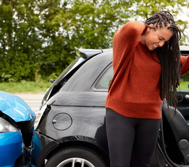 Female Motorist With Whiplash Injury In Car Crash Getting Out Of Vehicle