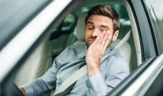 A tired driver rubbing his palm on his face