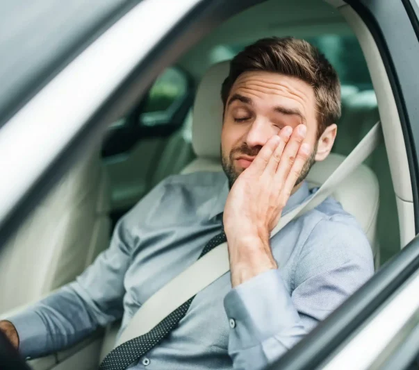 A tired driver rubbing his palm on his face