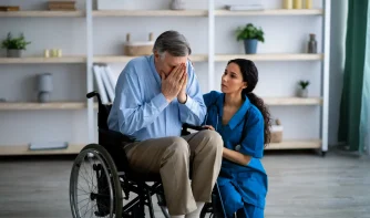 A nurse consoling a crying patient sitting on the wheelchair