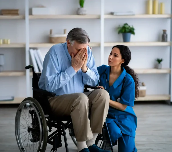 A nurse consoling a crying patient sitting on the wheelchair