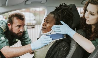 Paramedic placing a cervical collar to an injured woman from car accident