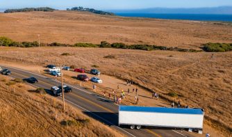 An aerial shot of vehicles and people on the highway surrounded by fields