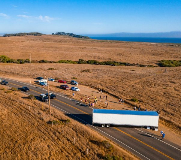 An aerial shot of vehicles and people on the highway surrounded by fields