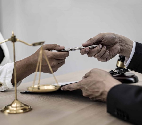 attorney handling client a pen to sign a document