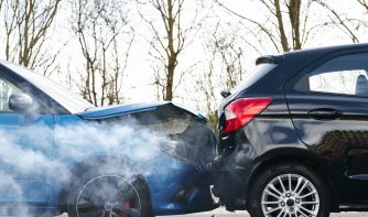 Two cars involved in traffic accident on side of the road with damage to bonnet and fender