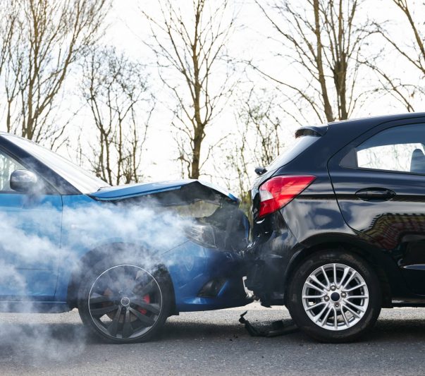 Two cars involved in traffic accident on side of the road with damage to bonnet and fender