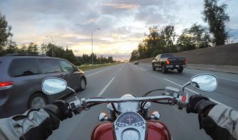 riding motorcycle next to vehicles during sunset